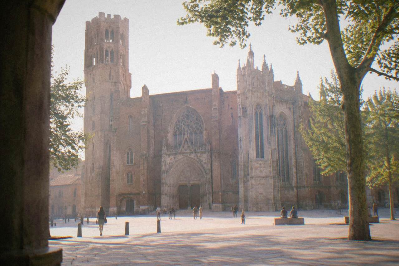 The wide brick facade of Toulouse Cathedral seen from the square in front of it