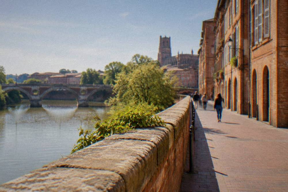 A narrow pink-brick street in old Toulouse leading toward the cathedral district