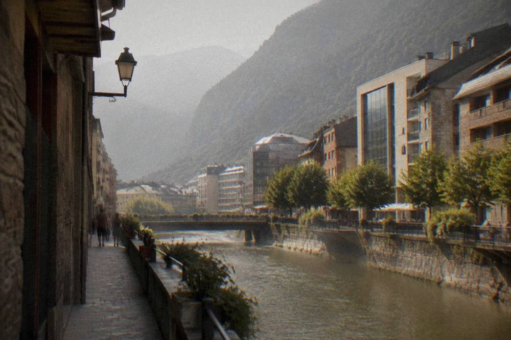 A narrow stone street with slate-roofed buildings and mountains in the background