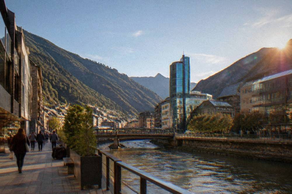 A modern glass spa tower rising above mountain buildings under a blue sky