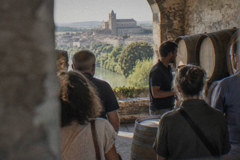 A small group of visitors standing around barrels listening to a cellar guide