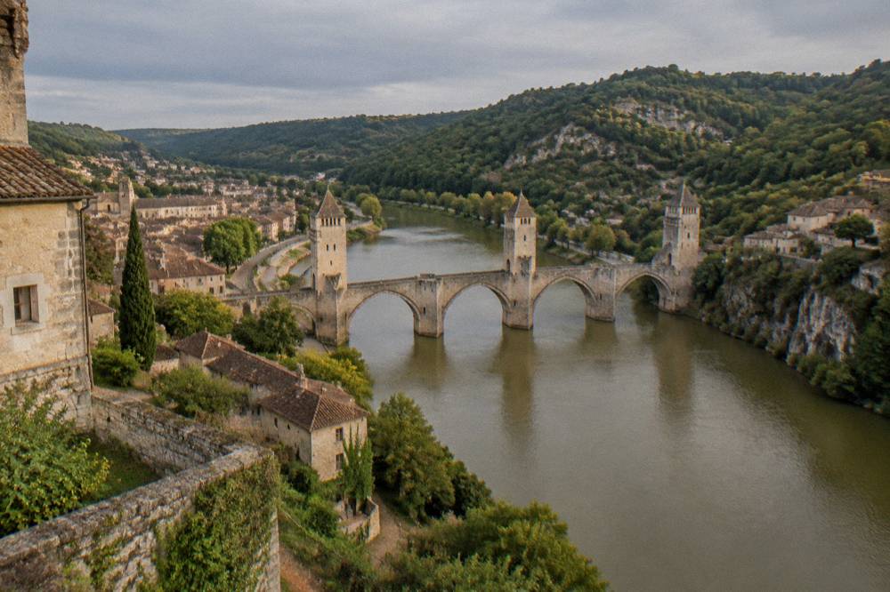 A stone village perched on a cliff above a winding green river valley