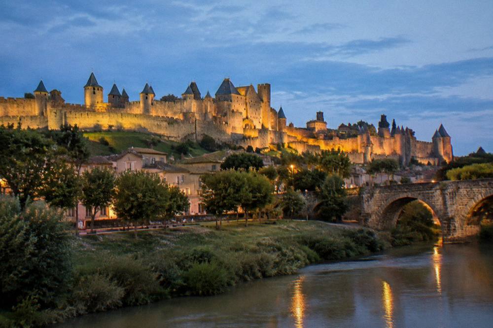 Illuminated medieval towers and walls at dusk with warm lights in the streets
