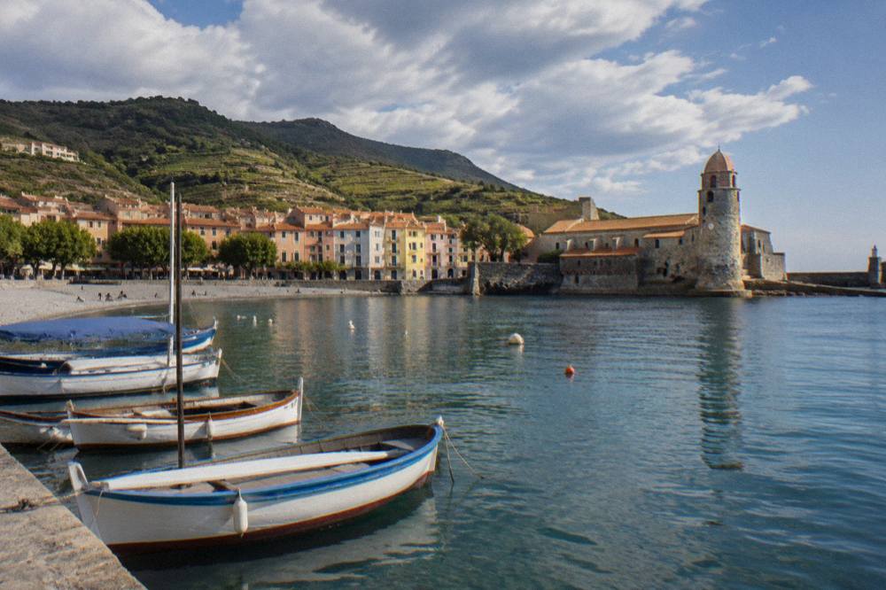 Small fishing boats moored in a Mediterranean harbor with hills behind