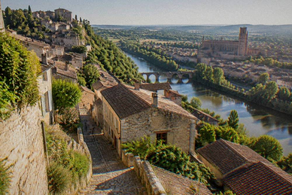 A red-brick cathedral and old town seen across a river in southwestern France