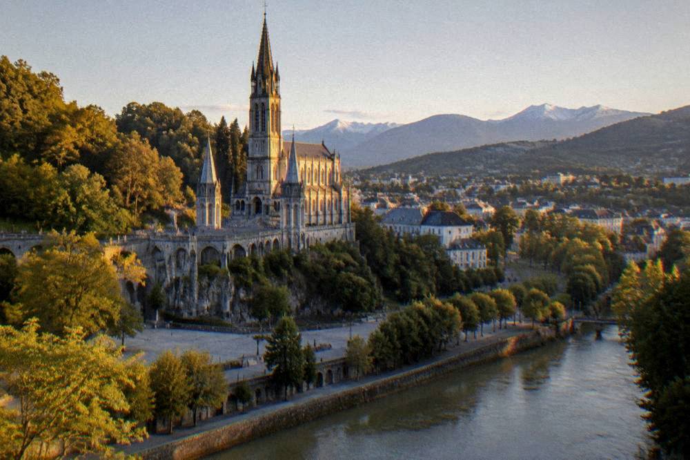 Evening light on the sanctuary spires with the town of Lourdes spread out below