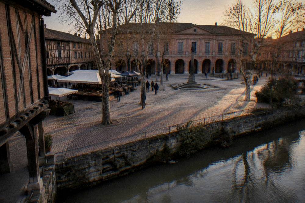 A pink brick city square with a columned facade seen across an open plaza at dusk