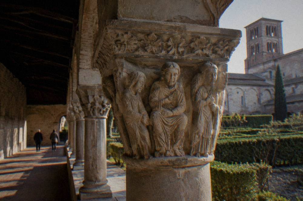 A carved stone capital with figures inside the cloister of Moissac abbey