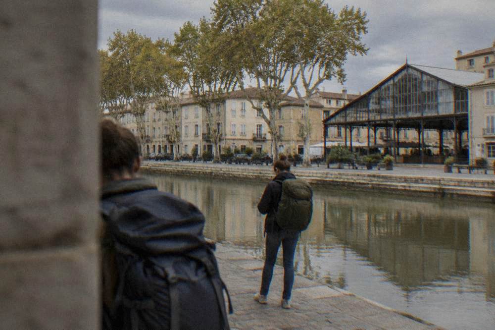 Travelers with backpacks checking the departure board in a French railway station