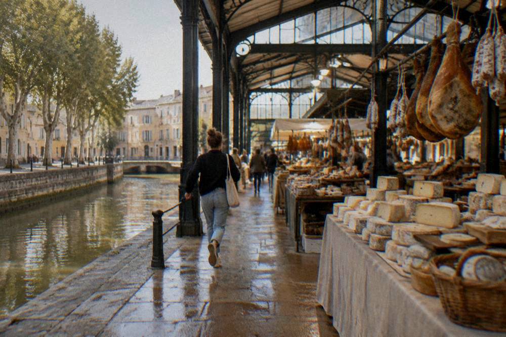 Market stalls with cheeses and cured hams under the iron roof of a French covered market