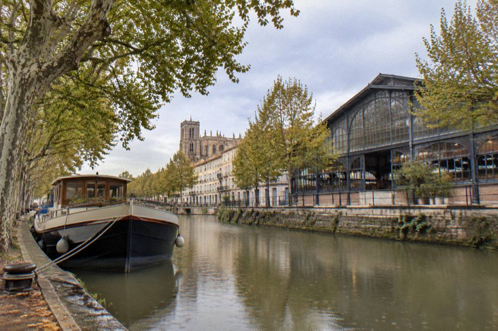 A canal boat moored along the tree-lined banks of a French canal