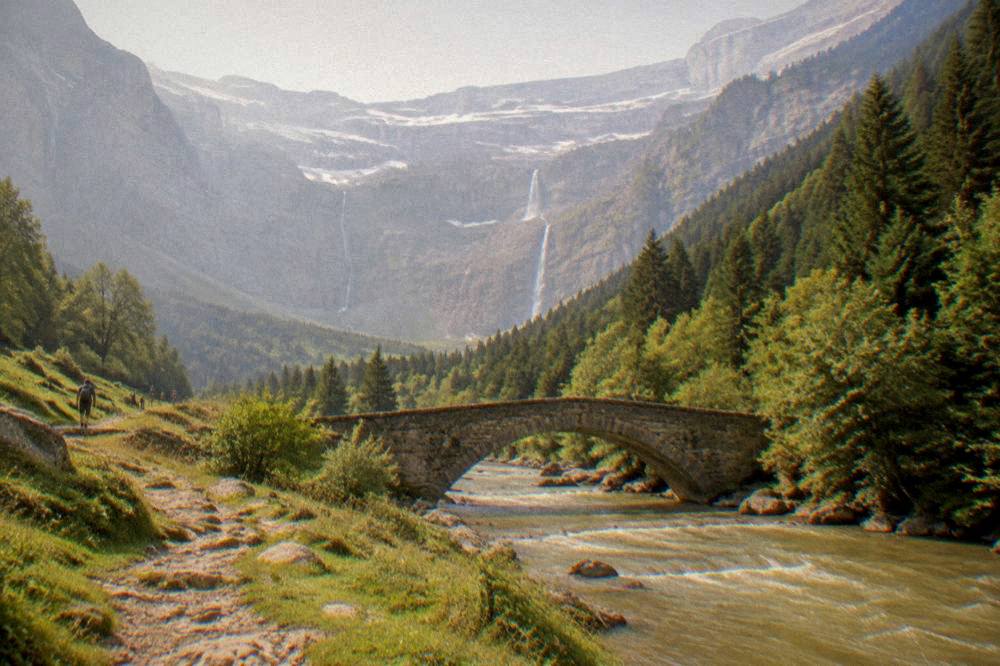 A stone bridge over a rushing mountain river with forested slopes on both sides