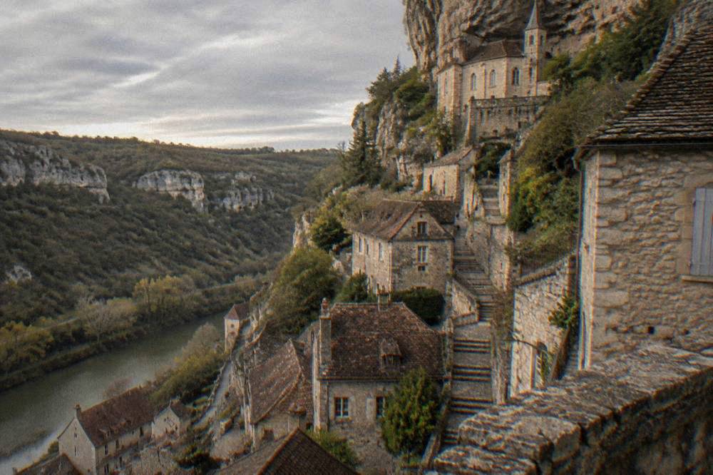 A stone staircase climbing between old buildings toward a chapel set into a cliff face.