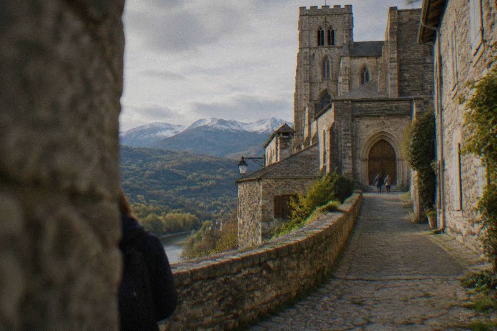 A narrow stone street climbing toward a cathedral entrance with wooden doors