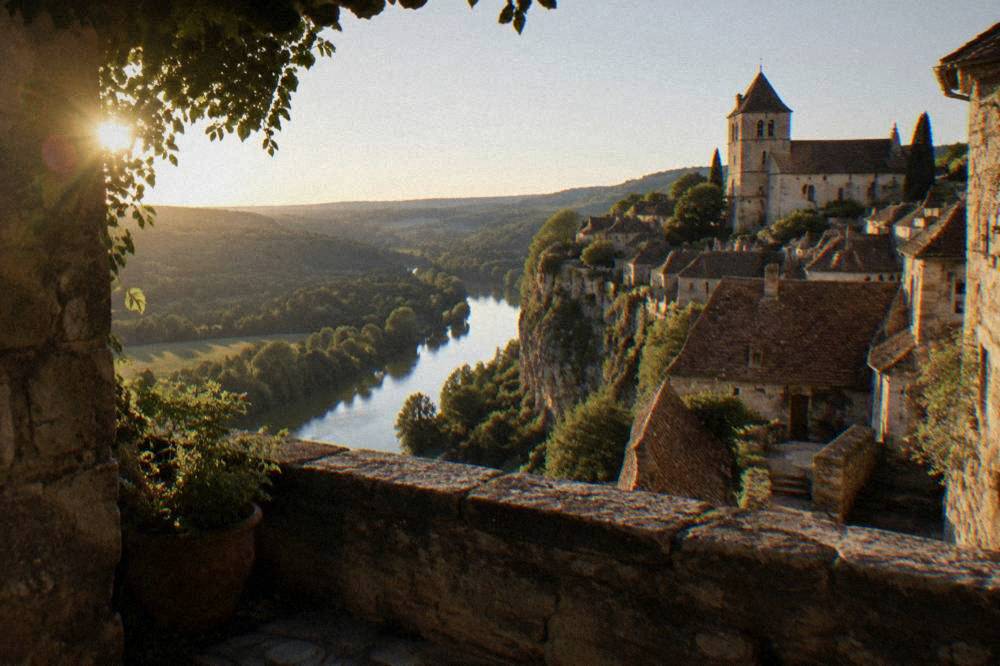 A view over a river valley from a stone terrace with a village church tower above