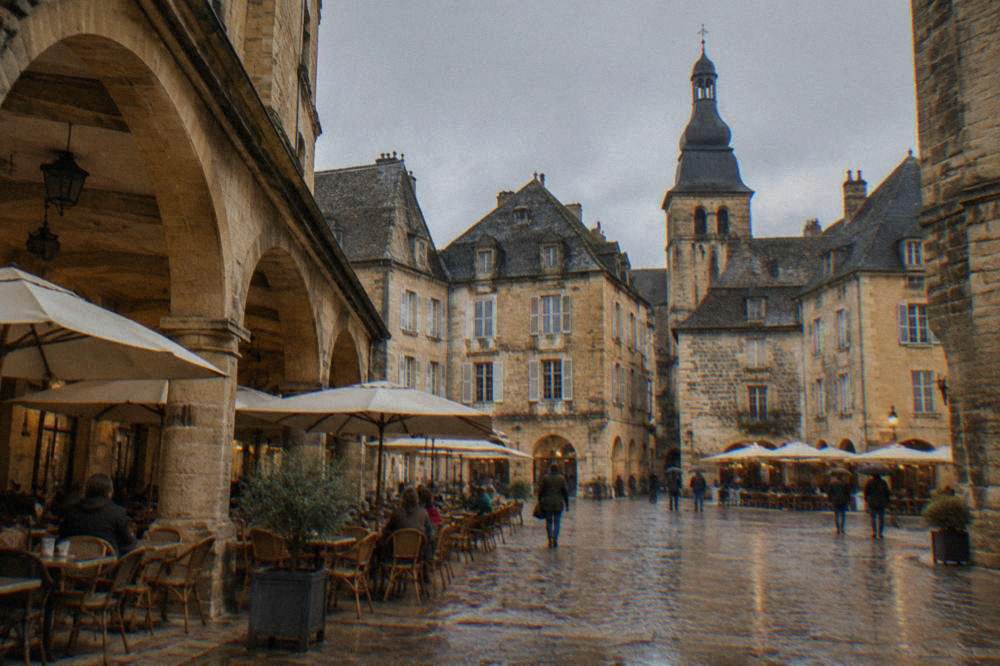 The Place de la Liberte in Sarlat with cafe terraces under stone arcades