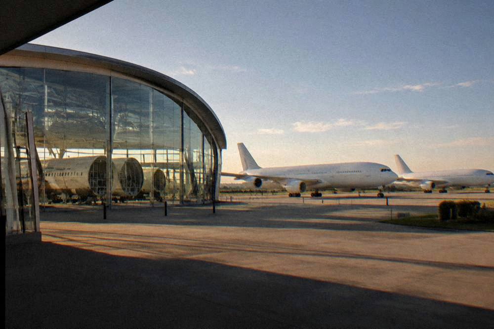Widebody airliner fuselage sections lined up inside a bright assembly hall