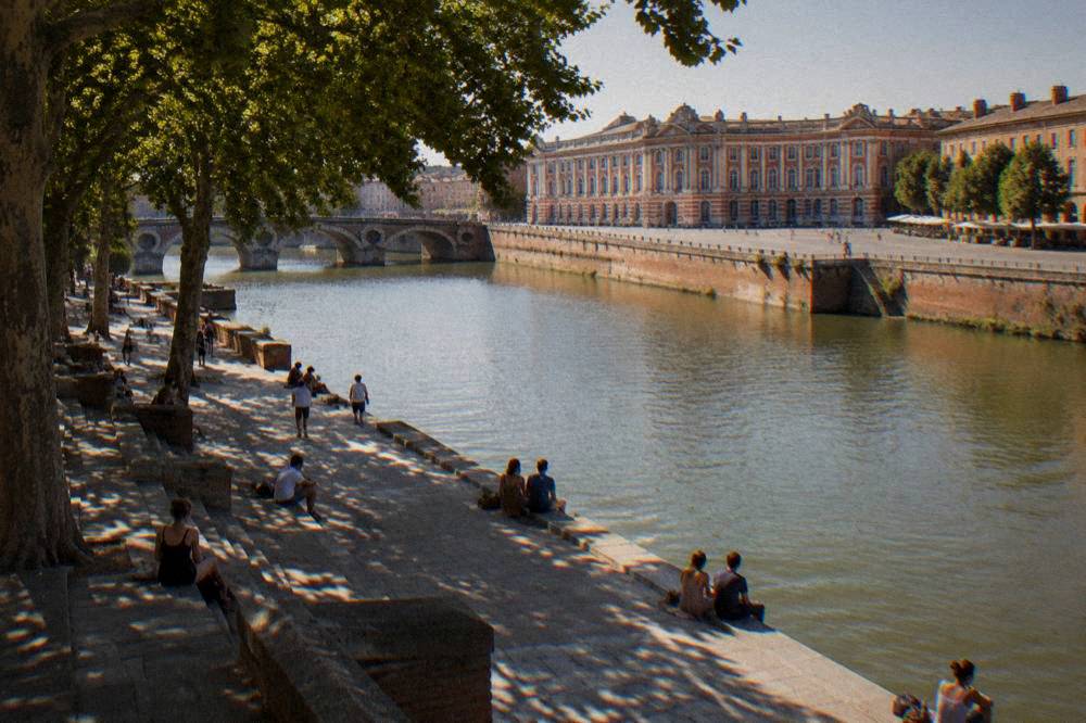 People relaxing in shade beside the Garonne river on a hot summer day in Toulouse