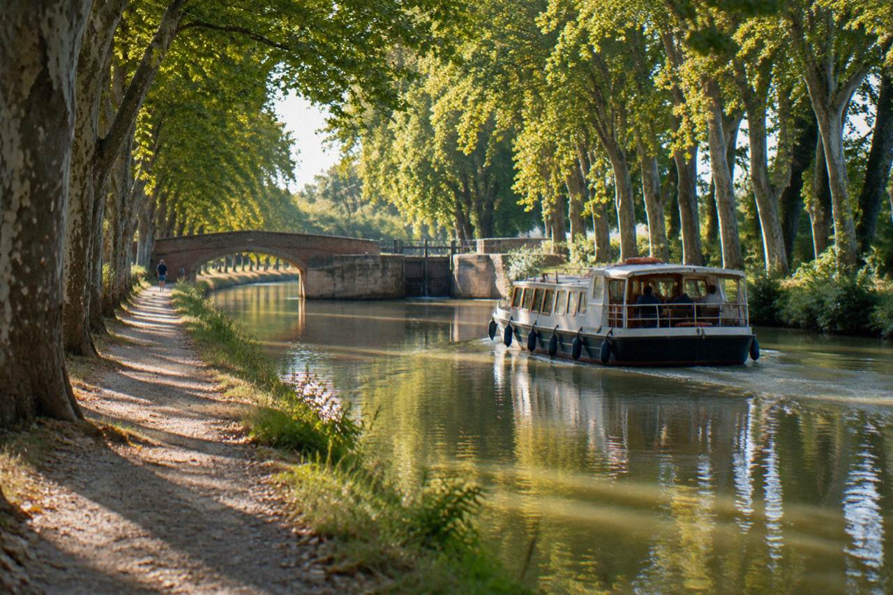 A canal boat gliding along the tree-lined Canal du Midi near Toulouse