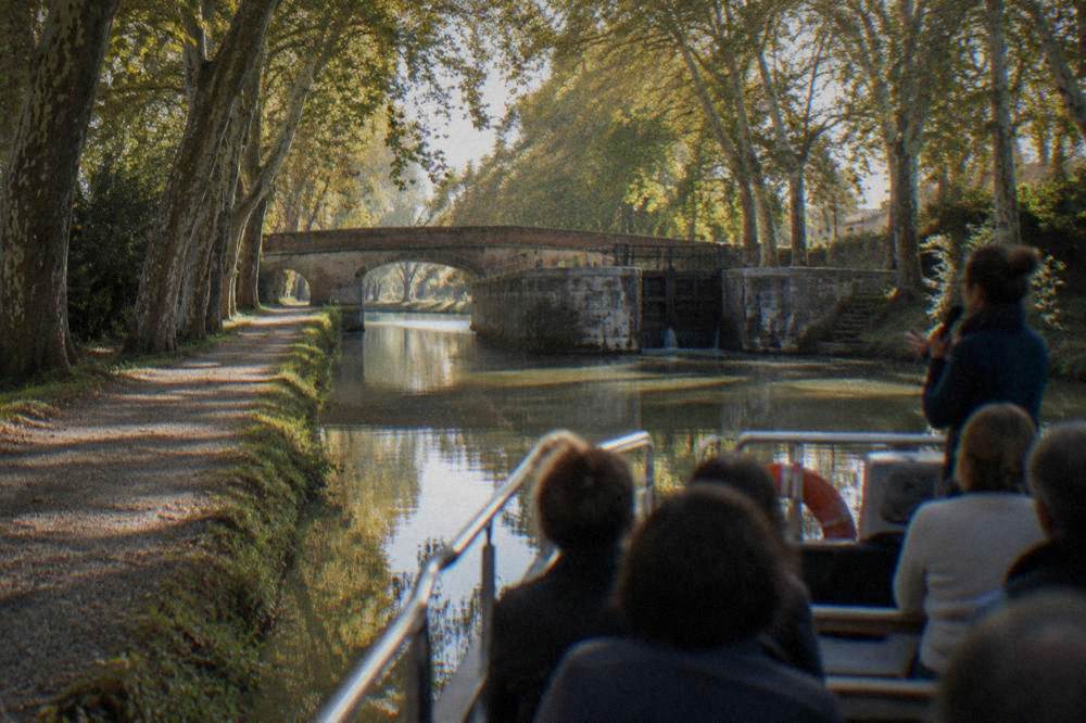 Passengers on an open canal boat listening to a guide's commentary