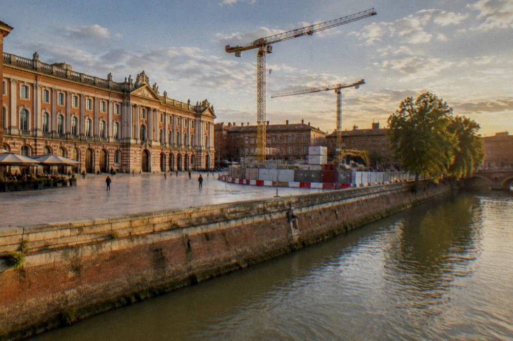 A construction site for the Toulouse Line C metro with cranes and barriers along a city street