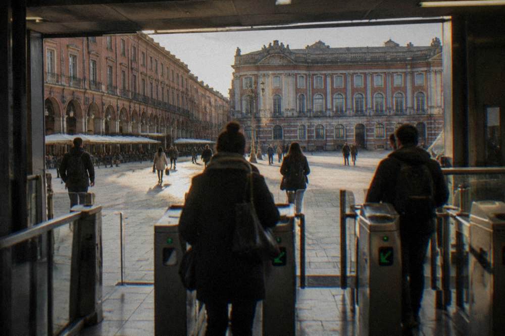 A metro station entrance in Toulouse with passengers passing through ticket gates