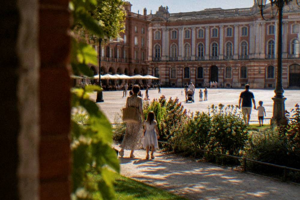 Families walking through a public garden in Toulouse on a sunny afternoon