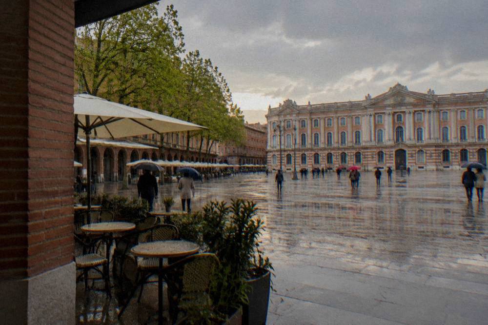 Umbrellas on a rainy spring day on a Toulouse street lined with pink brick facades