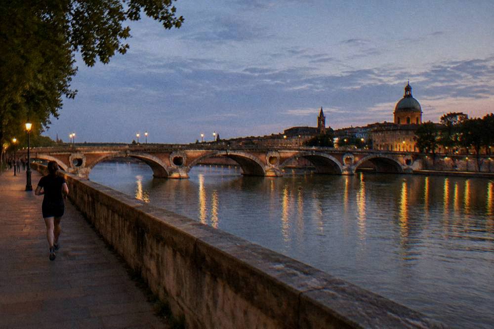 The Garonne river at dusk with the Pont Neuf and the lights of Toulouse reflected on the water