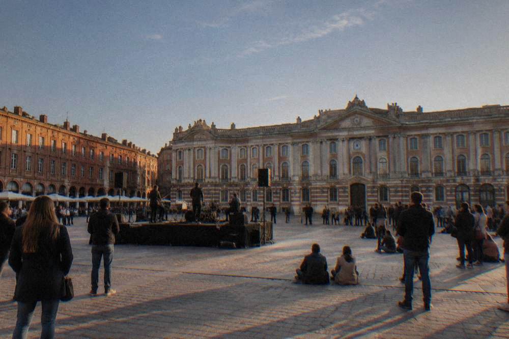 Musicians performing on an outdoor stage in a Toulouse square in the evening