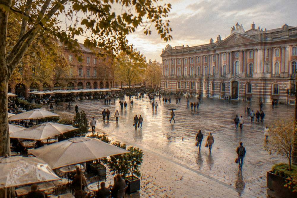An autumn street scene in Toulouse with plane trees and people walking past cafe terraces