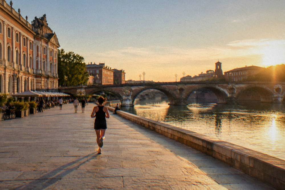 A river flowing under an old stone bridge in a French city at dusk