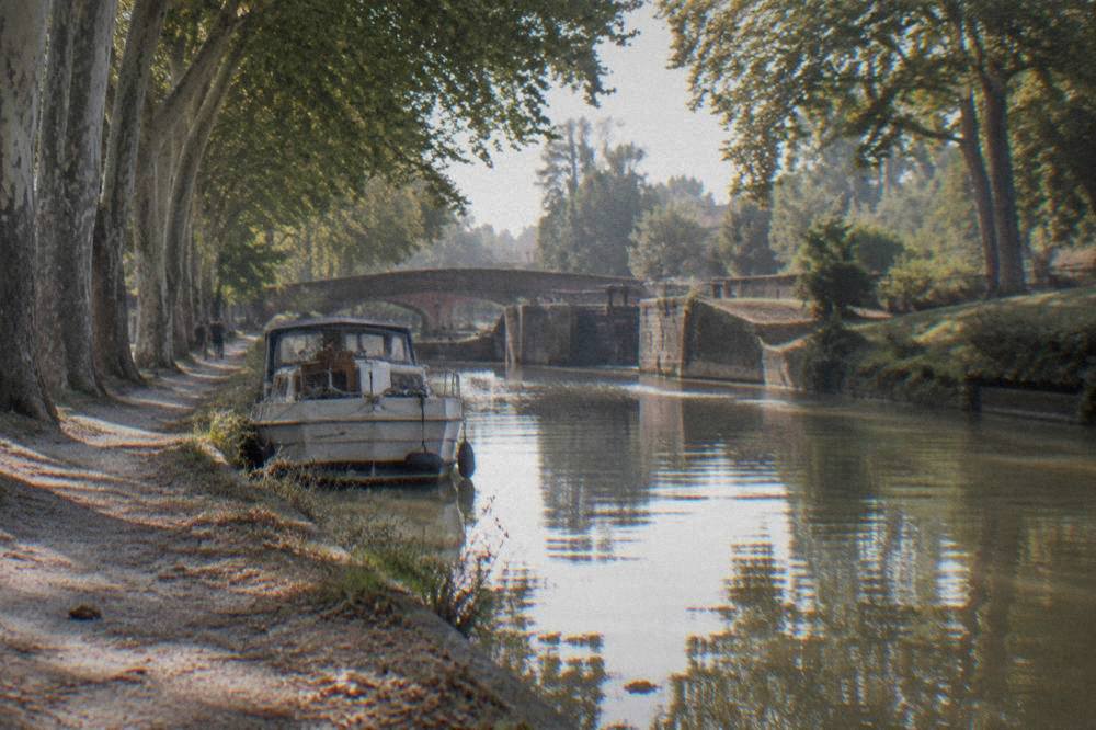 The tree-lined Canal du Midi with a pleasure boat moored along the bank
