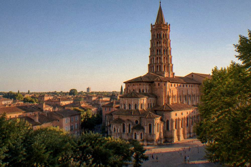 A sunny summer view over Toulouse rooftops with the Basilique Saint-Sernin tower rising above them