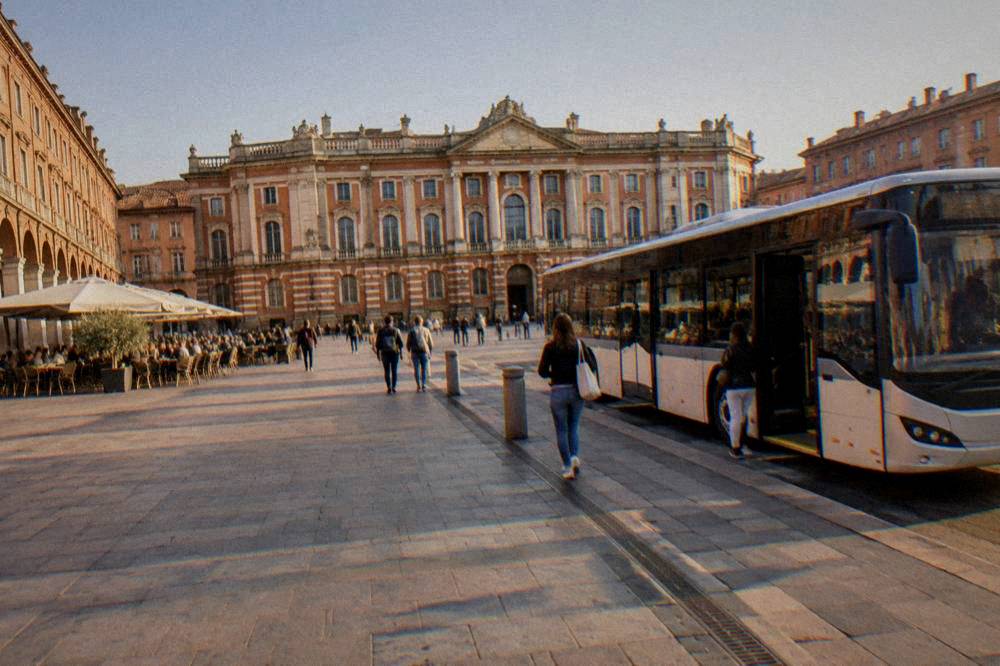 Modern Toulouse airport shuttle bus parked at a terminal curb with a boarding door open