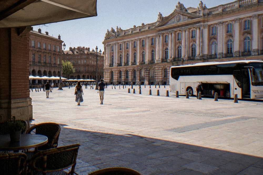 A white airport shuttle bus parked at a curb with its luggage doors open