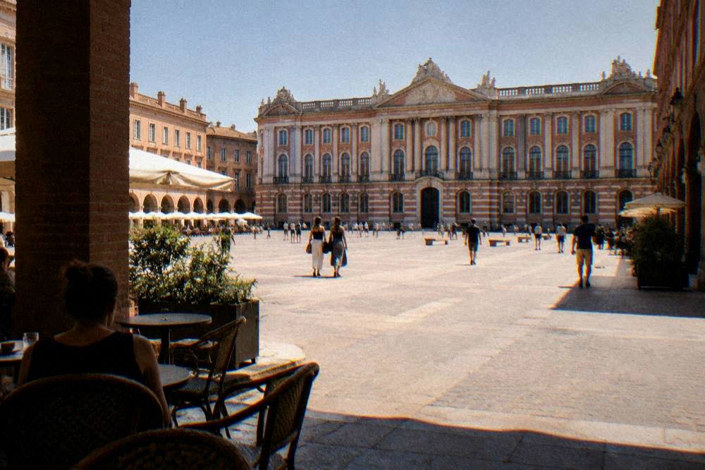 The pink brick facade and square of the Capitole in Toulouse under a clear sky