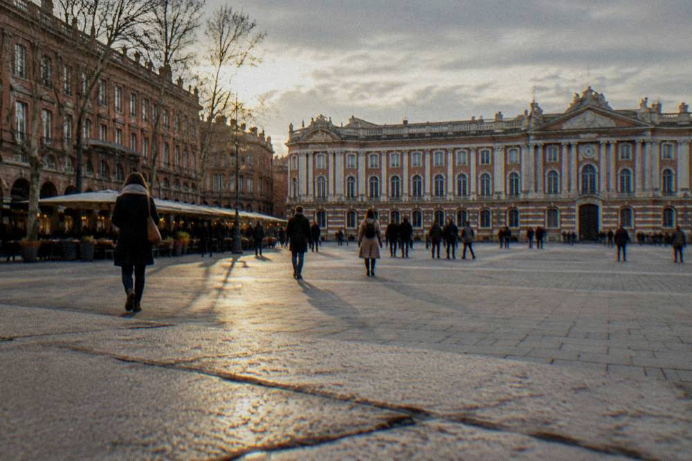 People strolling past illuminated shop fronts in central Toulouse in December