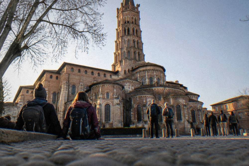 Pilgrim walkers resting outside the Basilica of Saint-Sernin in Toulouse