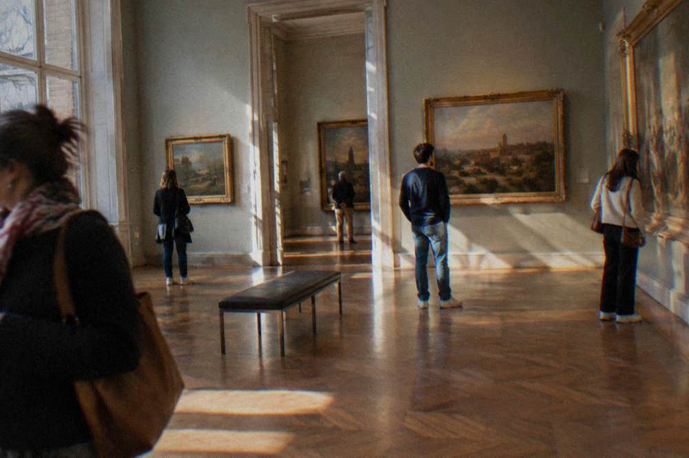 Visitors looking at paintings inside a Toulouse art museum gallery