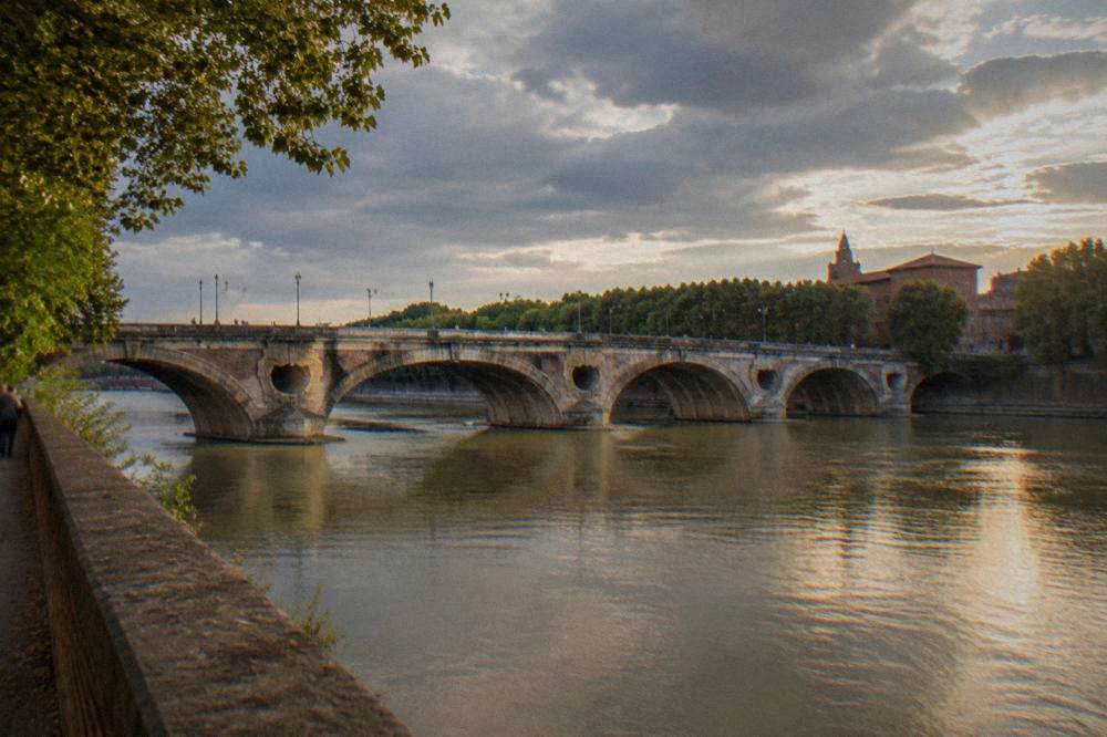 The Garonne river and Pont Neuf seen from the bank in evening light