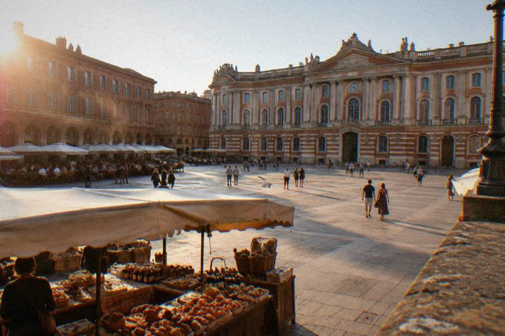 A market stall with pastries and regional products under the awnings of a Toulouse street market