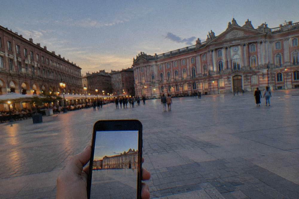 A smartphone showing a city map with a route line on a sunny plaza in Toulouse