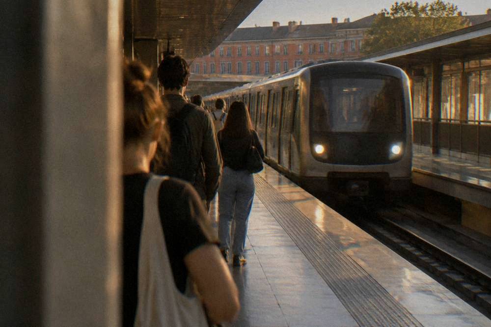 A metro station platform in Toulouse with a train arriving and passengers waiting