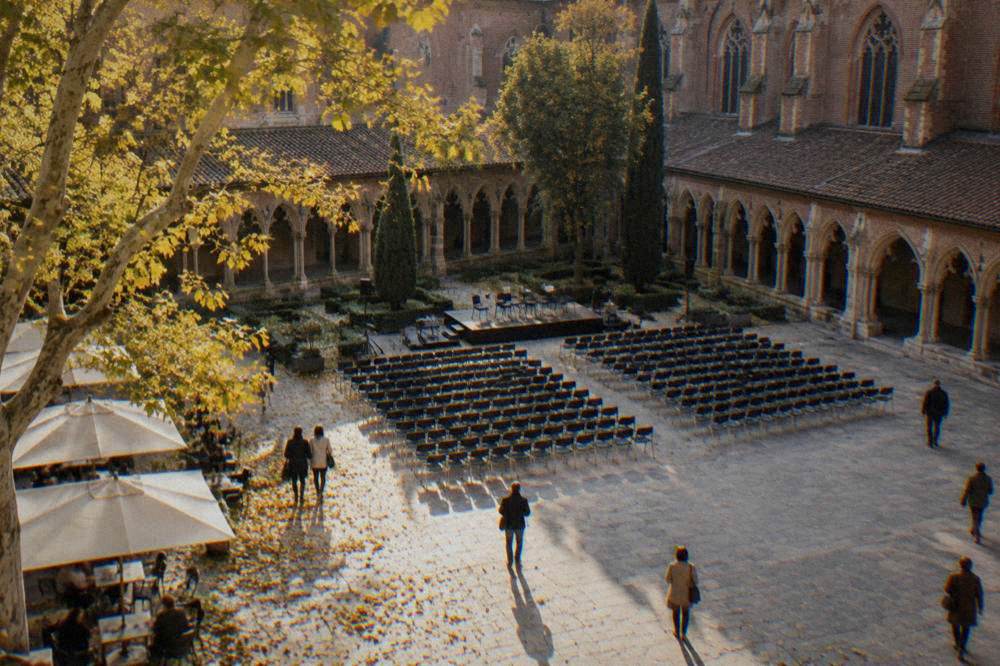 Autumn light on a Gothic cloister courtyard in Toulouse with rows of chairs set out for a concert