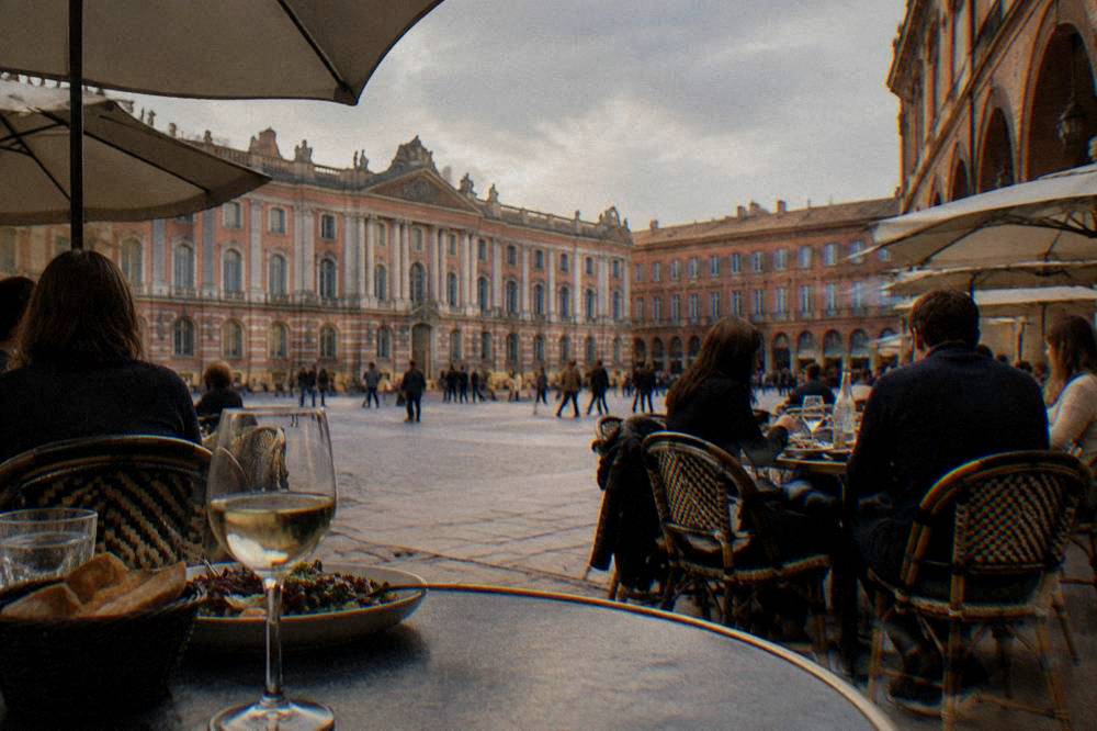 A busy bistro terrace with diners eating lunch in a Toulouse square