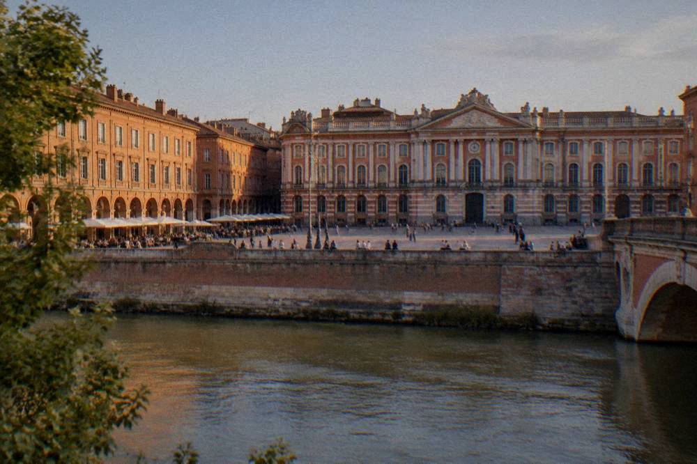 A sunny square in Toulouse with cafe tables and pink brick walls