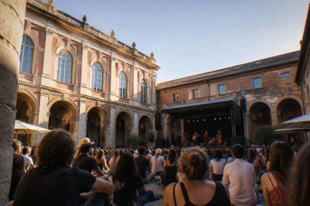 A concert crowd in a historic cloister courtyard in Toulouse
