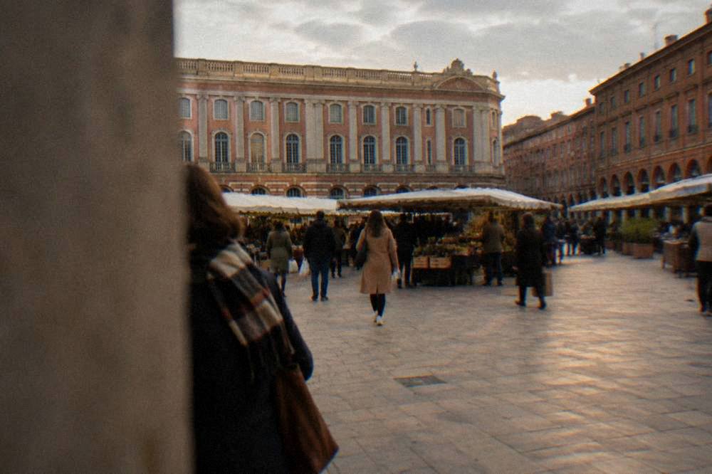 Shoppers walking between market stalls in a Toulouse square