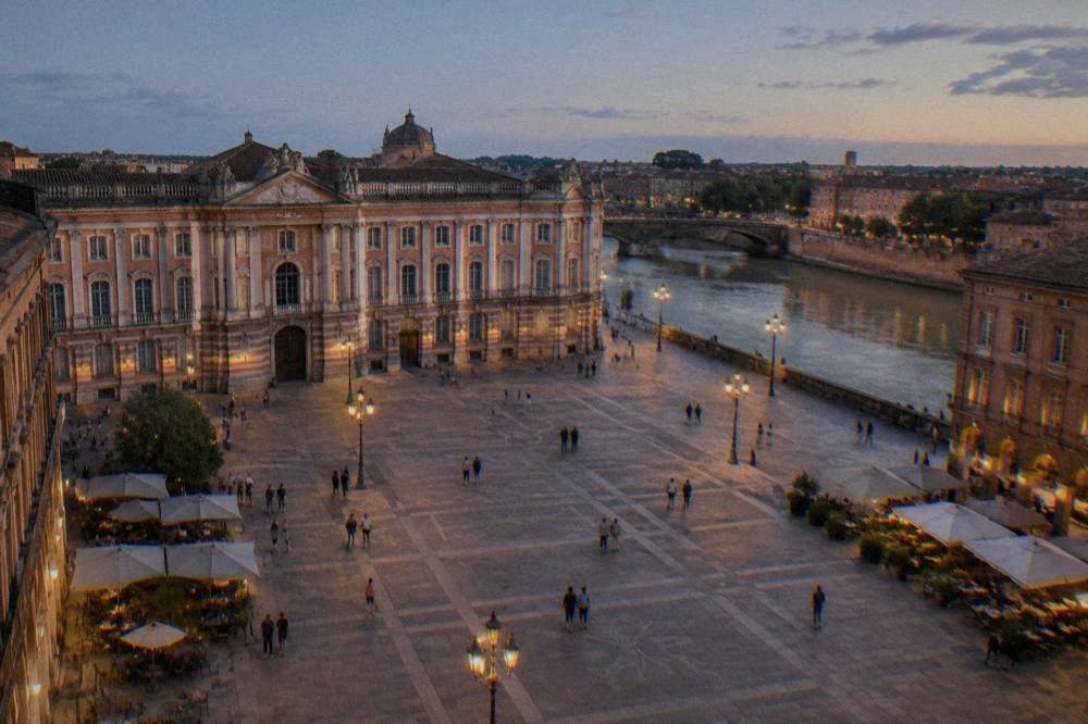 A stone quay along the Garonne in Toulouse with pink brick buildings glowing in evening light